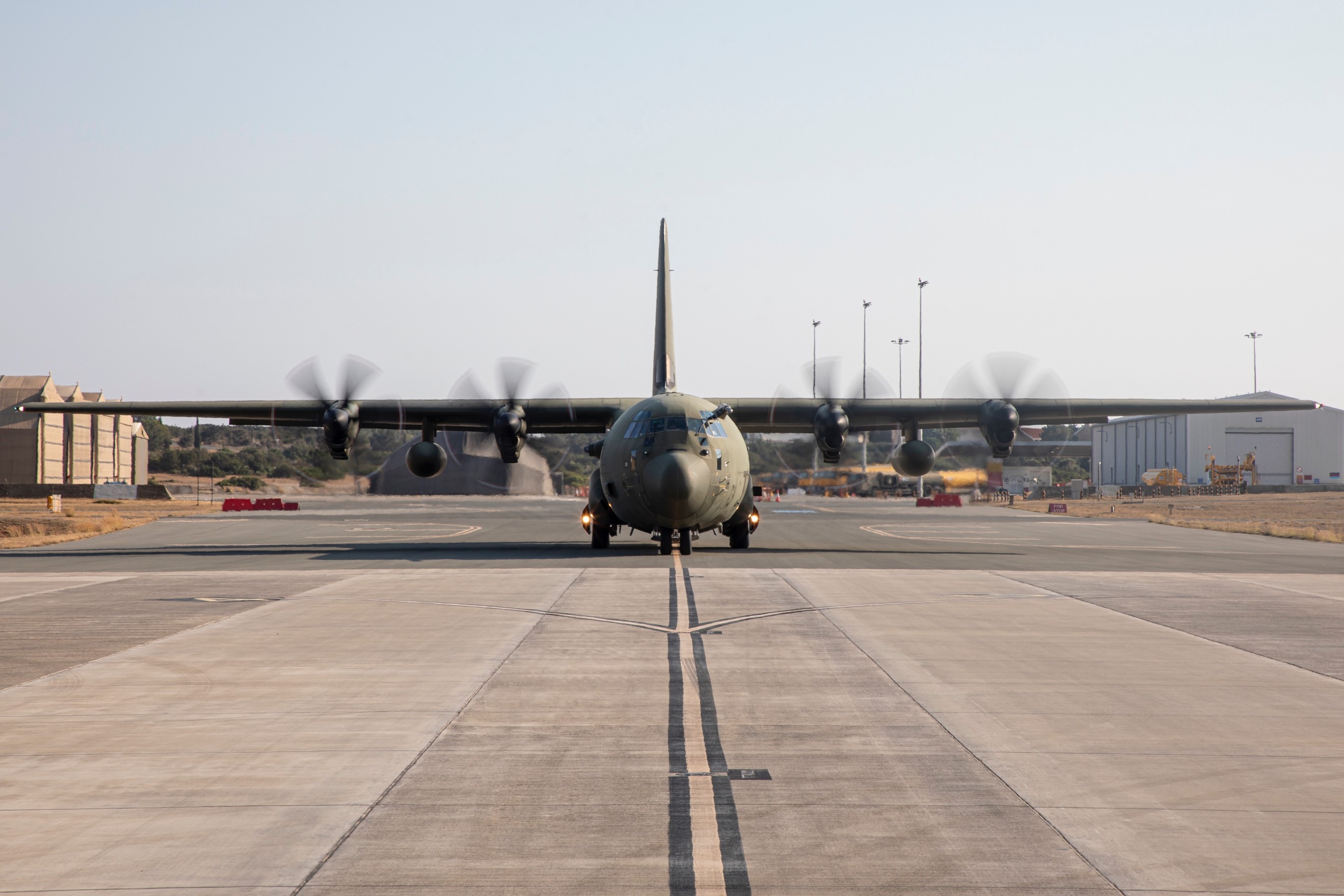 Image shows a C-130J Hercules on the runway about to take off.